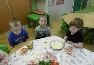 Troje dzieci siedzi przy stole.