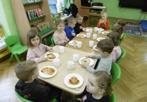 Dzieci podczas wspólnego spożywania pizzy.
