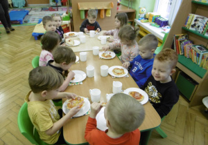 Dzieci podczas wspólnego spożywania pizzy.