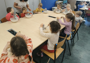 KOlejna grupa dzieci siedzi przy stole.