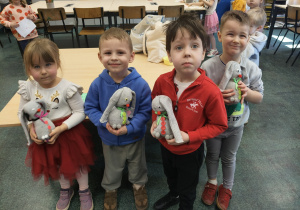 Czworo dzieci stoi obok siebie z wykonanymi pracami.