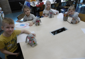 Kolejna grupa dzieci siedzi przy stole ze swoimi zabawkami.