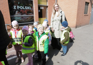 Nauczycielka i dzieci stoją razem przed budynkiem.