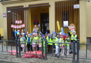 Grupa dzieci stoi razem przed przedszkolem.