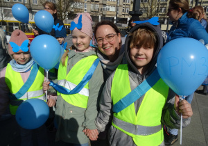 Troje dzieci i nauczycielka trzymają niebieskie balony.