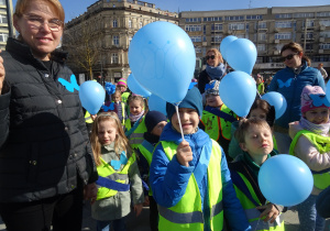 Dzieci i osoby dorosłe stoją obok siebie.
