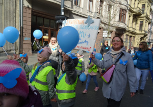 Grupa dzieci i pracownicy przedszkola idą w marszu.
