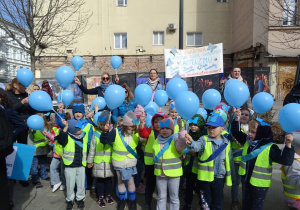 Grupa dzieci stoi razem z niebieskimi balonami.