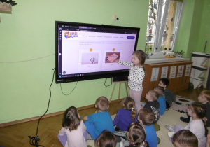 Dziewczynka stoi przy monitorze.