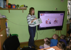 Nauczycielka pokazuje dzieciom apteczkę pierwszej pomocy.