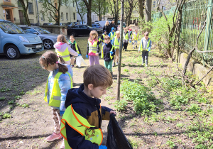 Chłopiec trzyma czarny worek na śmieci.