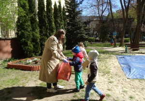 Nauczycielka pomaga trzymać worek na śmieci.