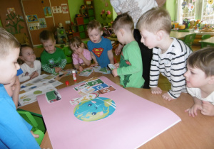 Dzieci wspólnie naklejają papierowe elementy.