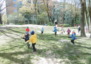 Dzieci zbierają śmieci z ogrodu przedszkolnego.