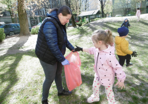 Dziewczynka wrzuca odpadek do plastikowego worka.