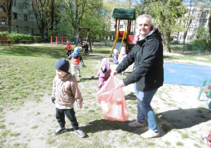 Pomoc nauczyciela stoi z workiem na śmieci.