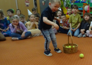 Chłopiec celuje żótymi piłkami do kosza
