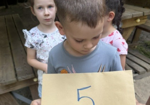 Chłopiec stoi z cyfrą nr 5.