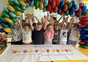 Dzieci trzymają się za ręce i tworzą łańcuch przyjaźni.
