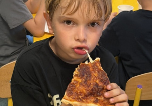 Chłopiec je pizzę.