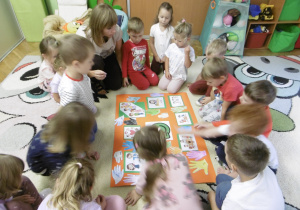 Grupa dzieci siedzi wokół wspólnej pracy.