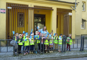 Grupa dzieci stoi przed wejściem do przedszkola.