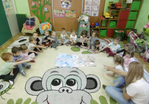 Dzieci siedzą w kole na dywanie.