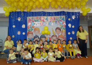Kolejna grupa dzieci siedzi na ławce i pozuje do zdjęcia.