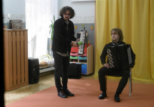 Dwóch muzyków stoi obok siebie.