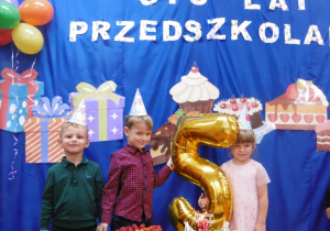 Troje dzieci stoi przed ciastami urodzinowymi.
