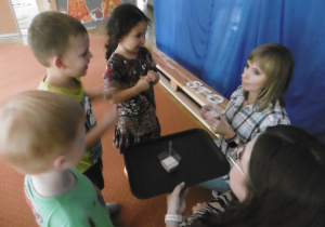 Nauczycielka i dzieci częstują sokiem kolejną panią nauczycielkę.