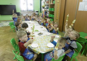 Cała grupa dzieci siedzi przy stole.