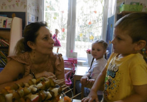 Dzieci częstują szaszłykami inną panią z obsługi.