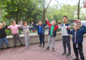 Juniorzy w przygotowaniach do występu z okazji Dnia Mamy i Taty w ogrodzie przedszkolnym ustawieni w półkolu