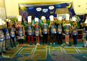 Żaczki ustawione w półkolu w strojach kucharzy podczas występów z okazji Dnia mamy i Taty