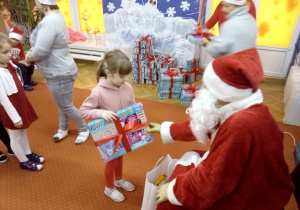 dziewczynka odbiera prezent od Św. Mikołaja