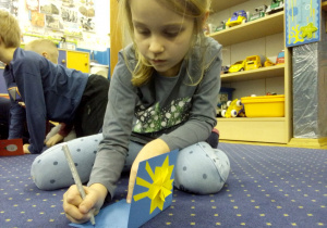 dziewczynka przygotowuje świateczną kartę - zapisuje życzenia świąteczne