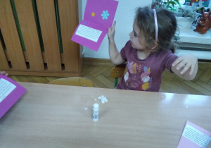 dziewczynka przy stoliczku przygotowuje laurkę dla Babci