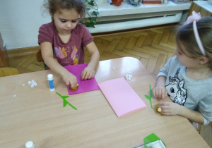 dziewczynka przy stoliczku przygotowuje laurkę dla Babci