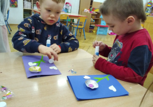 chłopcy przy stoliczkach przygotowują laurki dla Babci