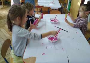 Smyki przy stoliczkach malują farbami