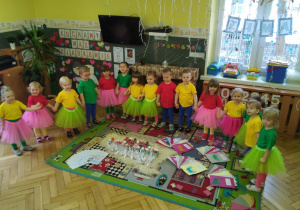 Tuptusie w kolorowych strojach ustawione w półkolu, na dywanie przygotowane dla Babci i Dziadka prezenty