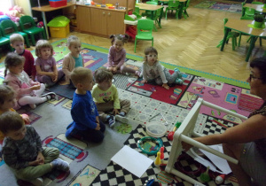 zajęcia logorytmiczne w Tuptusiach - dzieci siedzą na dywanie i odgadują jaki przedmiot wydaje dźwięk