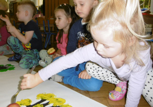 Tuptusie odbijają na kartce papieru jabłko zamoczone w farbie
