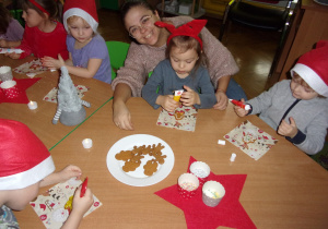 dzieci ozdabiają pierniczki przy stoliczkach