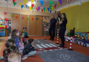 Strażnik Miejski opowiada dzieciom o sygnalizacji wskazując zielone światło