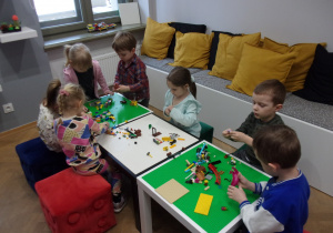 Smyki przy stoliczkach bawią się klockami lego