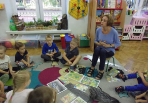 Smyki w kole na dywanie rozmawiają przy ilustarcjach tematycznych