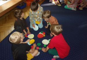 Juniorzy na dywanie ukłądają kompozycje z kropek dużych i małych