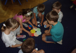 Juniorzy na dywanie ukłądają kompozycje z kropek dużych i małych